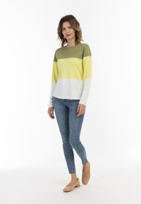 Maglione lavorato a maglia con strisce orizzontali verdi, gialle e bianche; abbinato a jeans blu e mocassini beige per un aspetto coerente.
