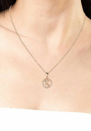 Gouden halsketting met een cirkelvormige hanger, voorzien van een textuurontwerp in het midden, omringd door kleine heldere edelstenen.