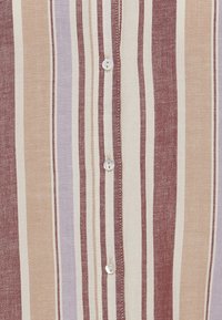 Chemise à boutons rayée présentant des lignes verticales dans des teintes de bourgogne, beige et lavande, avec un bouton blanc et un tissu texturé.