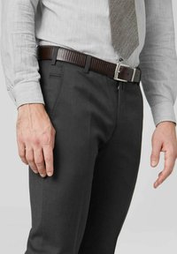 Pantalon gris avec une texture lisse, porté avec une ceinture texturée marron et une chemise gris clair, avec un motif subtil et une cravate grise.