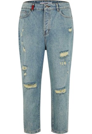 Jeans de mezclilla en azul claro con detalles desgastados, que presentan múltiples roturas, un diseño de cinco bolsillos y una etiqueta roja en la cintura.