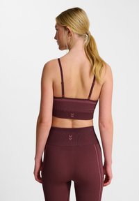 Bordeaux sportbeha met dunne bandjes, geribbelde textuur en subtiele chevron-accenten. Draagt samen met bijpassende hoge taille leggings.