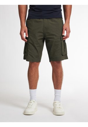 Shorts cargo verts olive en tissu léger, dotés de poches latérales et d'une coupe décontractée, associés à des chaussettes blanches et des baskets.