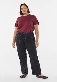 Burgundska bombažna majica, črne kavbojke z visokim pasom s trakcem za zavezovanje ter črni sijoči balerinki z okrasnim okovjem.