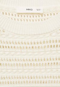 Maglione bianco lavorato a maglia con motivi a rete aperta, colletto rotondo e un'etichetta con scritto "MNG" che indica la taglia EUR-USA S.