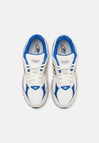 Baskets de course blanches et bleues avec une tige en maille, un col rembourré et un système de laçage ; comportent un accent noir et un logo sur le côté.