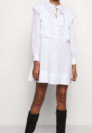 Robe blanche à texture rayée, manches longues et accents à volants. Comprend une fermeture à nouer au niveau du cou et un ourlet évasé. Bottes noires montant jusqu'aux genoux.