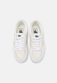 Par de zapatillas Vans blancas con cordones blancos, diseño de puntera perforada y logo "Vans Off The Wall" en la lengüeta y la plantilla, vista superior.