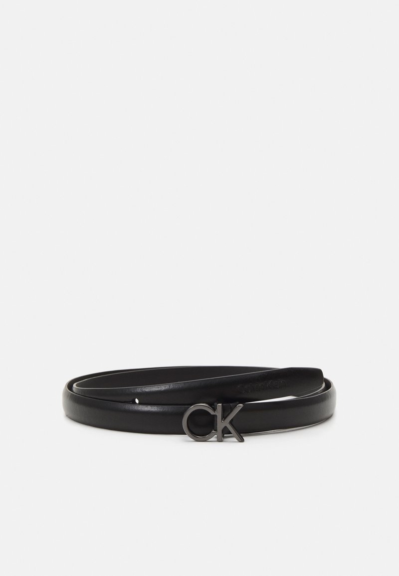 Ceinture fine en cuir noir avec boucle métallique aux initiales "ck", enroulée sur un fond clair uni.