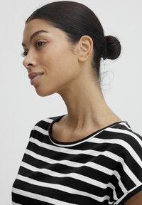 Camiseta de rayas en blanco y negro con mangas cortas, escote redondeado y textura de tela suave. Presenta rayas horizontales de igual ancho.