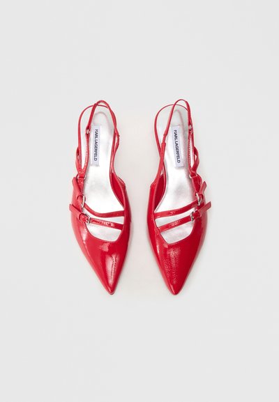 Red patent leather slingback heels with pointed toes, featuring two strap accents secured with metal buckles and a shiny silver interior.
