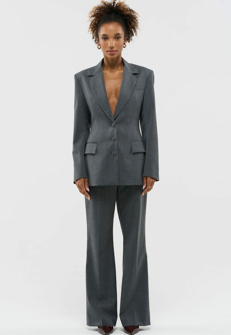 Grijze op maat gemaakte套; bestaande uit een dubbelgeknopte blazer met notched revers en wijde broekspijpen, met een subtiele gestreepte textuur en twee voorzakken.