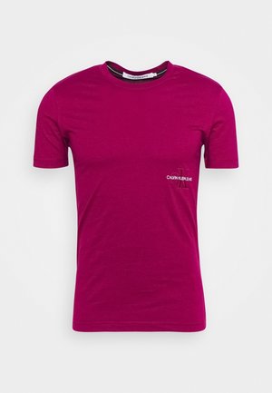 Krótki rękaw, głęboki magenta t-shirt Calvin Klein Jeans z małym logo na lewej piersi, okrągły dekolt, prezentowany na białym tle.