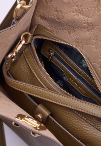 Zielona torebka ze skóry oliwkowej o fakturze pebble, z złotymi elementami i wzorzystym beżowym wnętrzem z wieloma zamykanymi kieszeniami.