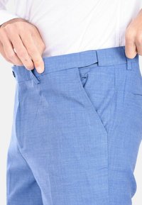 Pantaloni eleganti blu chiaro in tessuto testurizzato, con frontale piatto, tasche laterali e una cintura con passanti.