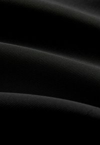 Schwarzer Stoff mit glatter, strukturierter Oberfläche und feinen Rippungen. Das Material wirkt weich und dicht, mit Falten, die subtile Schatten erzeugen.