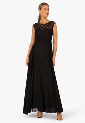 Abito da sera nero con busto in pizzo e gonna fluida a forma A. Il design senza maniche presenta delicati dettagli in pizzo e una morbida texture del tessuto.