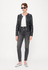 Crna jakna od umjetne kože s okruglim izrezom, uparena s bijelom majicom, sivim uskim trapericama i srebrnim ravnim cipelama. Elegantni dizajn.