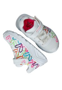 Zapatillas blancas con patrones de corazones coloridos en rosa, naranja, verde, azul y púrpura. Tienen un diseño perforado y una correa de velcro.