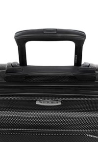 Harde zwarte koffer met een textuur, telescopische handgreep en zilveren hardware-details. Heeft een merklogo plaat.