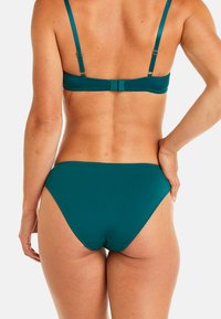 Ensemble de bikini teal comprenant un soutien-gorge ajustable avec des fines bretelles et un bas taille haute assorti, fabriqué en matériau lisse et extensible.