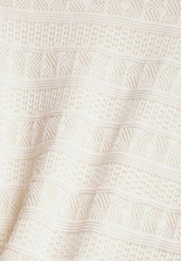 Tissu en maille blanche avec des motifs géométriques texturés alternés comprenant des losanges, des points et des lignes horizontales.