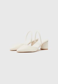 White pointed-toe slingback shoes with a smooth leather finish, featuring a narrow strap and a low block heel.
