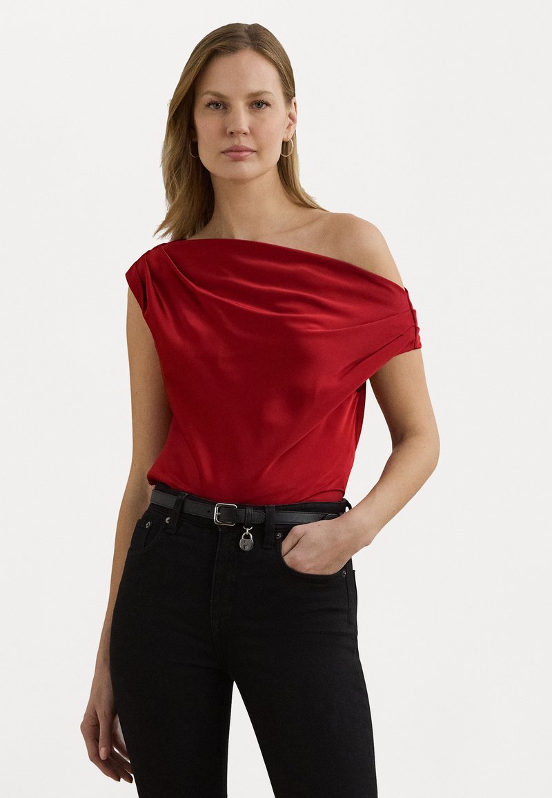 Röd satin av axeln-top med draperad detalj, kombinerad med höga svarta jeans och ett svart bälte med en liten silverdetalj.