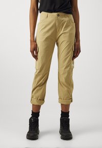 Khaki cargobyxor med uppvikta benslut, flera sidofickor och logodetalj. Tyget verkar vara lätt och har en slät textur. Bärs med svarta kängor.