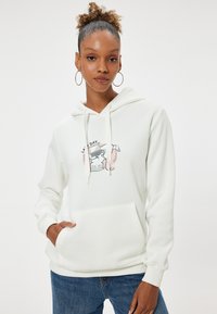 Sudadera de algodón blanca con un bolsillo frontal, que presenta una impresión gráfica de un gato y un portátil. Mangas largas, capucha con cordón, textura suave.