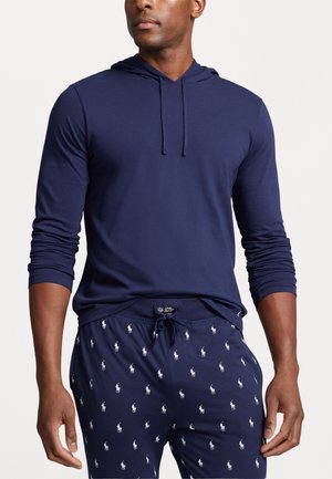 Navy long-sleeve hoodie with drawstring, paired with patterned navy pajama pants featuring small white polo logos throughout. Soft fabric texture.