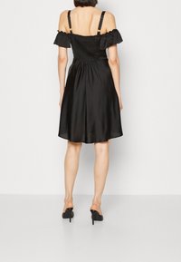 Černé saténové šaty s přiléhavým nařaseným živůtkem, odhalenými rameny a rozšířenou sukní. Součástí jsou nastavitelné ramínka a délka ke kolenům.