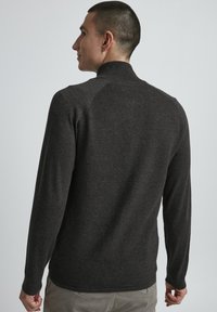 Maglione grigio scuro a maglia con collo alto e maniche lunghe, caratterizzato da un motivo a costine testurizzato sulla schiena e sulle spalle.