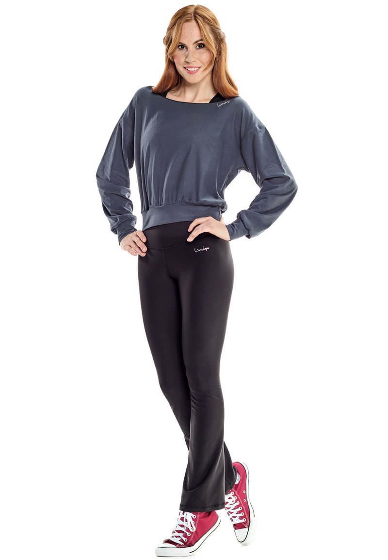 Gray long-sleeve top with a rounded neckline, paired with black fitted leggings and red sneakers. Sweatshirt features a logo detail.