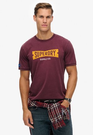 Bordeaux korte mouwen t-shirt met het logo "SUPERDRY SUPPLY CO." in geel. Katoenen stof, ronde halslijn, gecombineerd met een geruite shirt om de taille geknoopt.