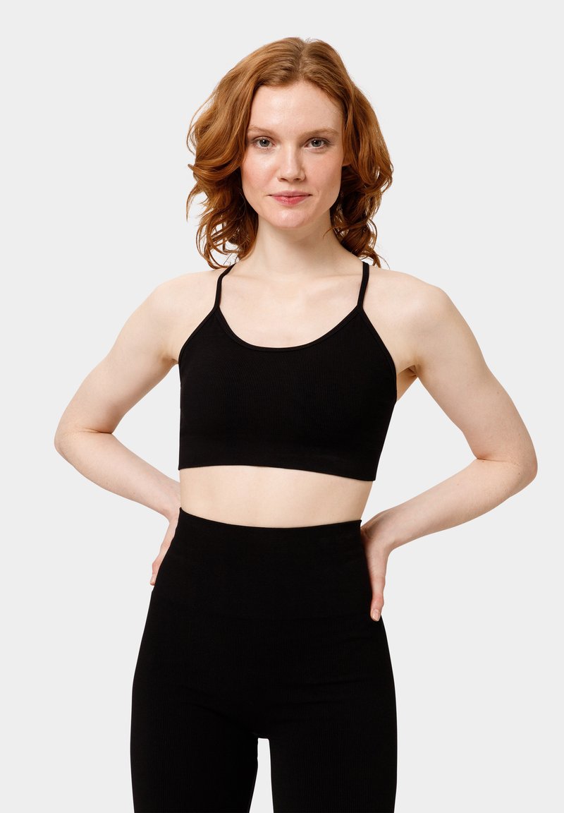 Top corto nero a coste con sottili spalline e scollatura arrotondata, abbinato a leggings neri a vita alta. Tessuto liscio, design minimalista.