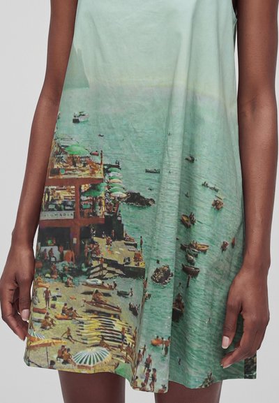 Robe sans manches avec un imprimé coloré d'une plage bondée, des parasols, des bateaux et des personnes près d'une jetée au bord de l'eau.