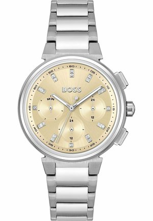 Montre en acier inoxydable argenté avec un cadran doré, trois sous-cadrans, des marqueurs en cristal et un bracelet en maillons métalliques. Nom de la marque "BOSS" affiché.