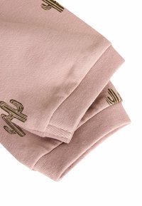 Rosa gestrickter Stoff, gefaltet, mit grünen Kaktusmustern. Weiche Textur mit glatter Oberfläche, die ein einfaches und sauberes Design zeigt.