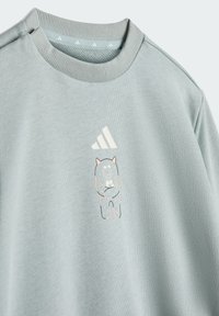 Svetlomodrá mikina vyrobená z mäkkej tkaniny s grafickým motívom rozprávkového hrdinu a ružovými akcentmi, s logom Adidas na ľavom hornom rohu.