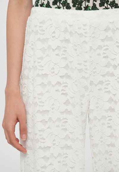 Pantaloni bianchi in pizzo con un motivo floreale, caratterizzati da un tessuto testurizzato e una vestibilità ampia. La vita è elastica per garantire comfort.