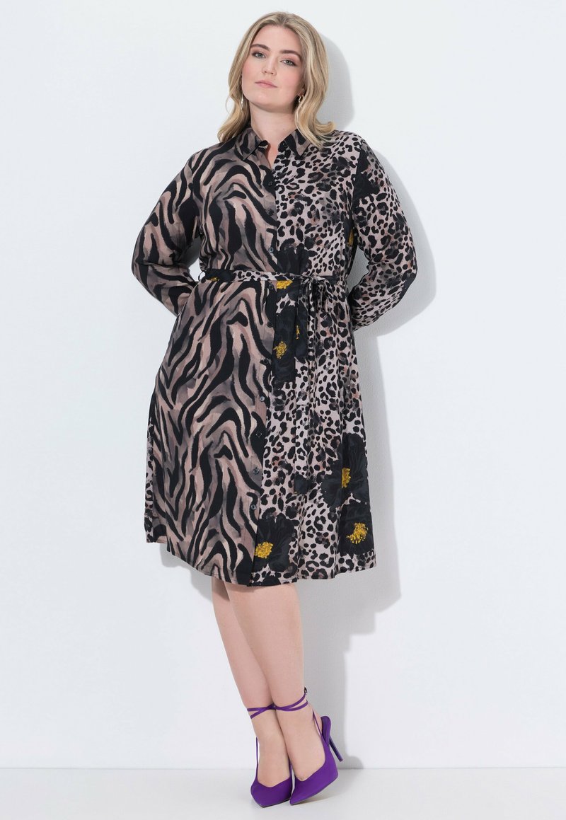 Abito a maniche lunghe con un design a spacco, motivi zebra e leopardo, colori nero e beige, vita cinchata e dettagli floreali.
