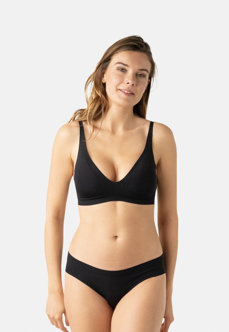 Bralette en coton noir avec un décolleté en V profond, des fines bretelles et un shorty noir assorti. Texture lisse, design ajusté, coutures minimales.