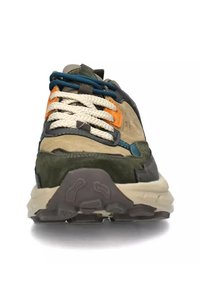 Sneakers verdi e grigi con tomaia testurizzata, dettagli accentuati in arancione e blu, suola grossa bianca e marrone, e lacci intrecciati.
