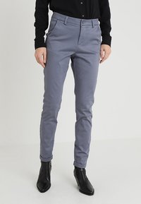 Ljust grå, skräddarsydda byxor med smal passform, med en slät yta, bälteshällor och uppvikt fåll, kombinerat med svarta ankelstövlar.