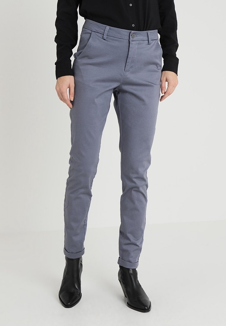 Ljust grå, skräddarsydda byxor med smal passform, med en slät yta, bälteshällor och uppvikt fåll, kombinerat med svarta ankelstövlar.