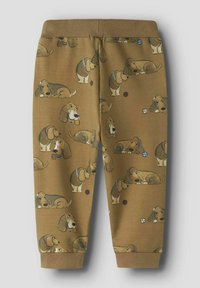 Bruna, mjuka joggers i tyg med ett lekfullt hundmönster, med elastisk midja och smalnande ärmar, perfekta för avslappnad användning.