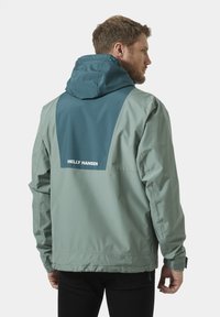 Lichtgewicht, groene waterdichte jas met een teal bovenpaneel en een verstelbare capuchon. Heeft elastische manchetten en een logo op de achterkant.