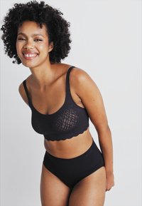 Black bralette with a textured, lace-like design and scalloped edges, paired with high-waisted black underwear. Smooth fabric finish.