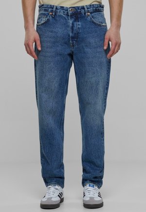 Jean en denim bleu clair avec une coupe décontractée, cinq poches et une fermeture à bouton. Présente une texture décolorée et des coutures contrastantes.